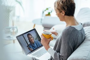 Woman sitting on the sofa while making video call over laptop with her doctor.